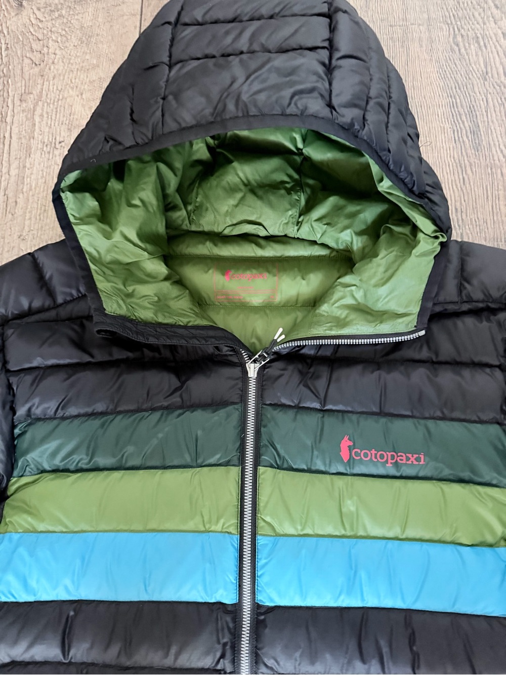 Cotopaxi Black Hooded Puffer with Green and Blue Chest Stripes - Picture 2 of 3